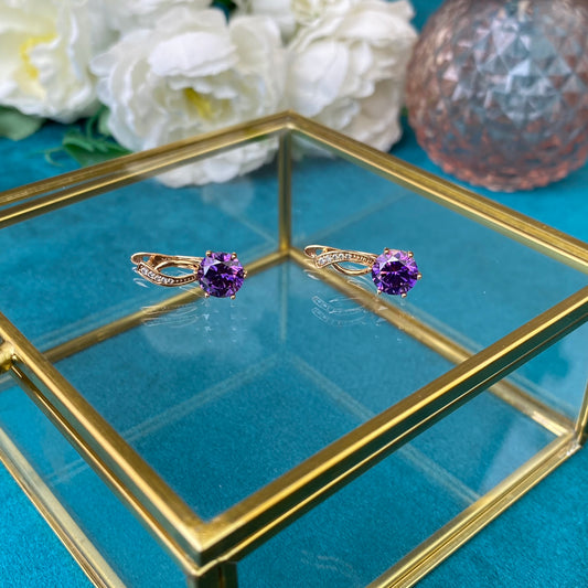 Apzeltīti auskari ar violetu dekoratīvu kristālu